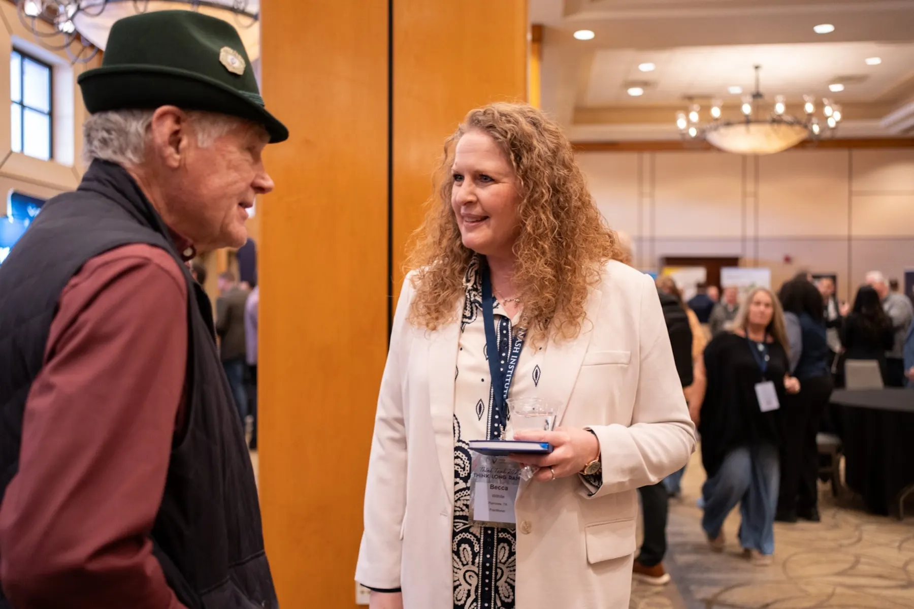 A longtime attendee in Nelson Nash's green Tyrolean hat talking with a colleague at Think Tank 2026
